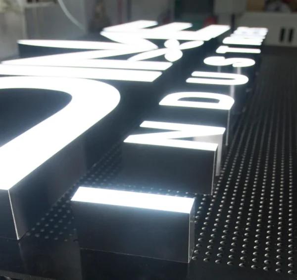 Illuminated 3D business sign with bold white letters on a black background, spelling out name. The sign features a sleek, modern design with raised letters that emit a bright, even glow, suitable for professional and industrial settings.