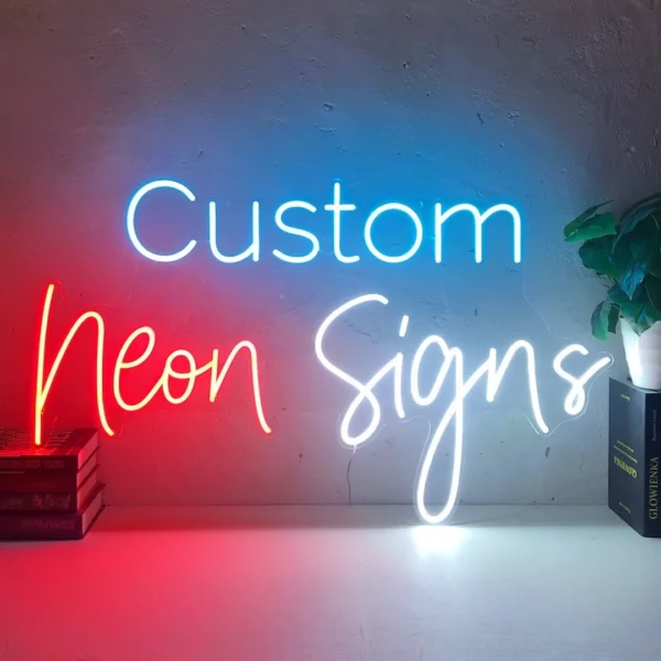 Neon sign displaying the words "Custom Neon Signs" mounted on a plain wall. The word "Custom" is in blue, "Neon" in red, and "Signs" in white.