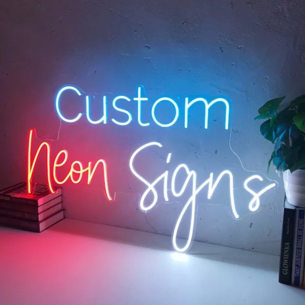 Neon sign displaying the words "Custom Neon Signs" mounted on a plain wall. The word "Custom" is in blue, "Neon" in red, and "Signs" in white.