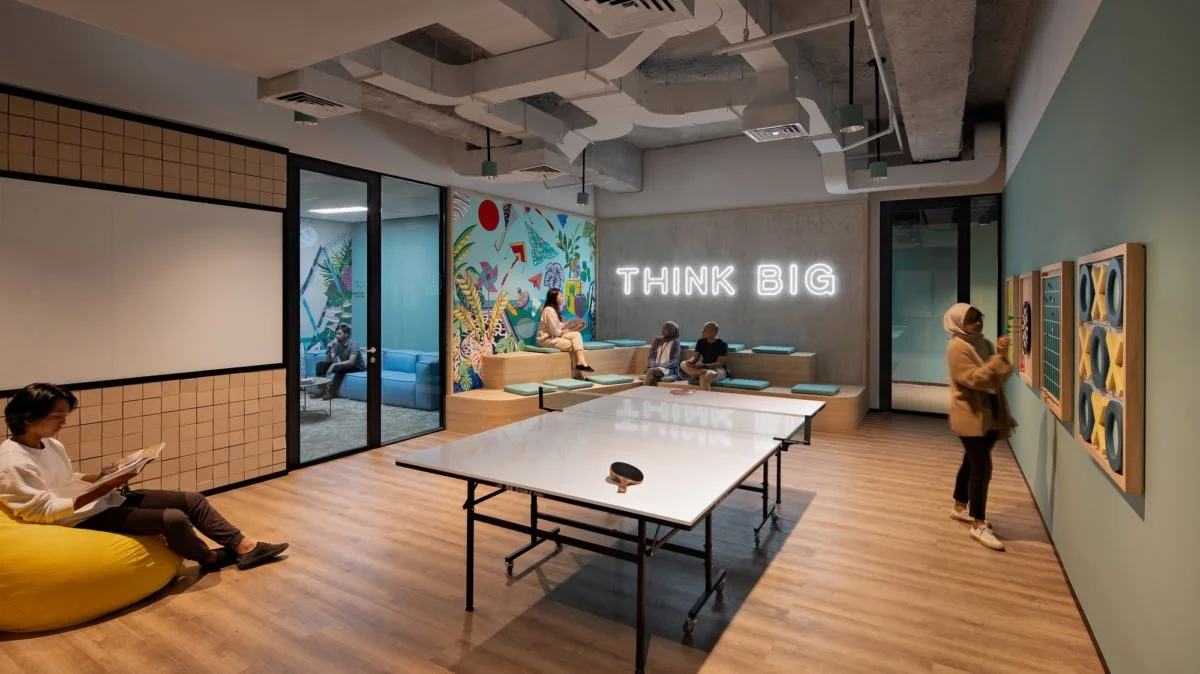 Modern office lounge area featuring a neon sign with the phrase "THINK BIG" mounted on a wall.