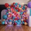 Colorful balloon backdrop with large neon lights forming the number "30."