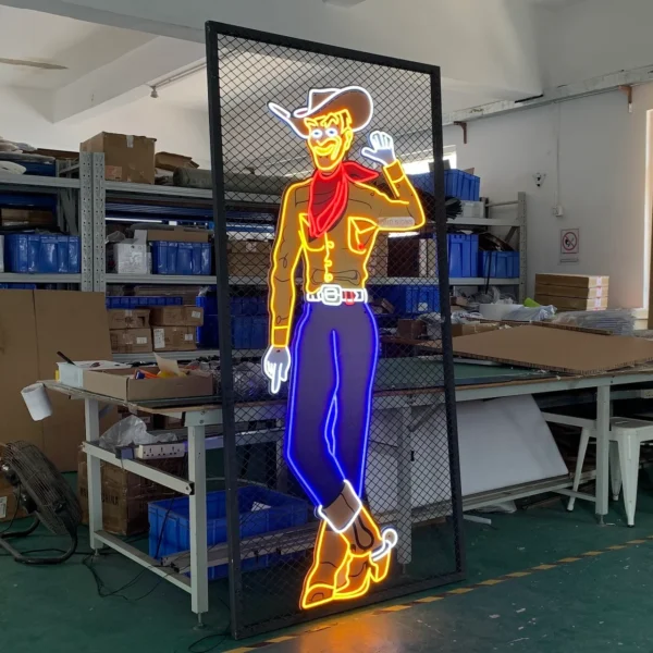 Neon sign of a cartoon cowboy waving, featuring vibrant yellow, red, and blue colors, displayed on a metal grid in a workshop.