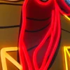 Close-up of a neon sign showing detailed red and yellow neon tubing forming part of a cowboy's bandana.