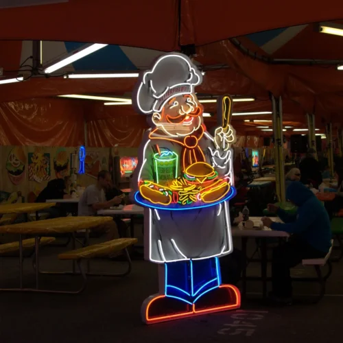 Neon sign of a cheerful chef holding a tray with a burger, fries, and a drink, set in a food court.