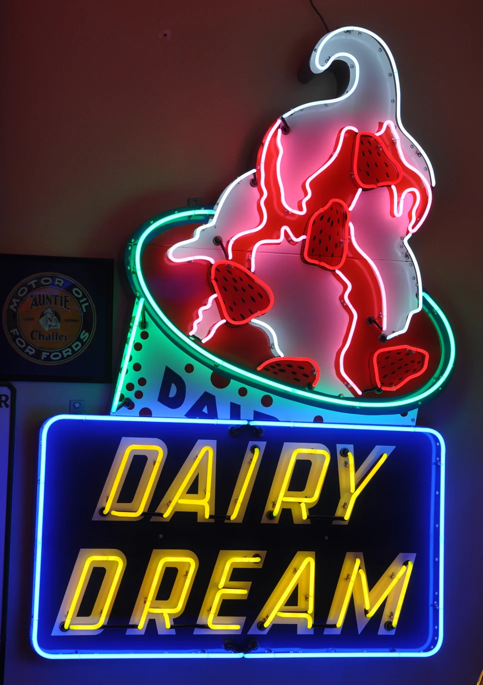 Neon sign of a Dairy Dream ice cream cone with strawberries on top. Below it, a blue and yellow neon sign spells out "Dairy Dream."